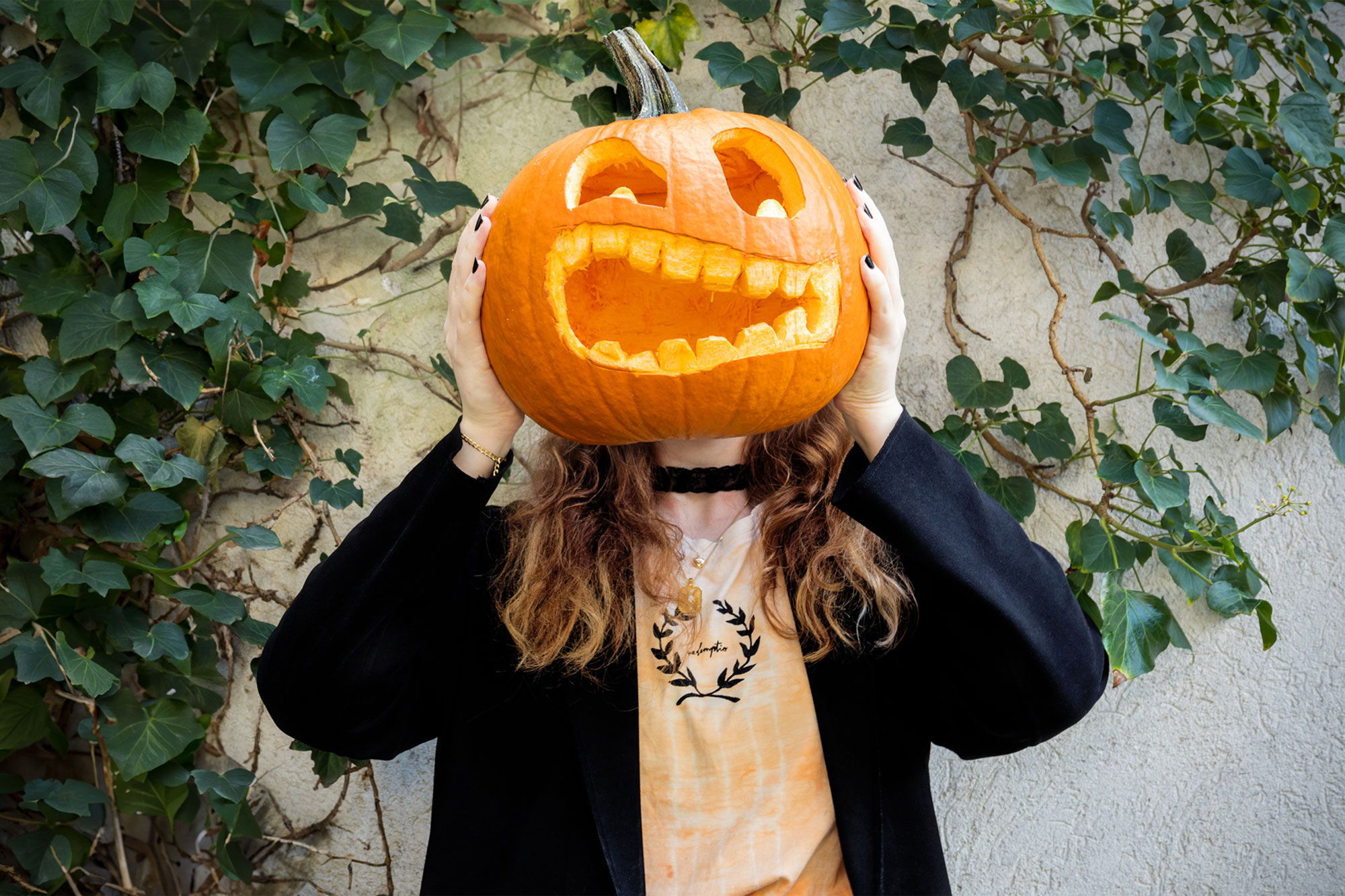 A picture of a girl holding a carved pumpkin in front of her face, it look like her real head ist this carved pumpkin
